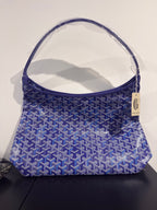 Blue patterned mini bag with top handle and small hanging label on side.