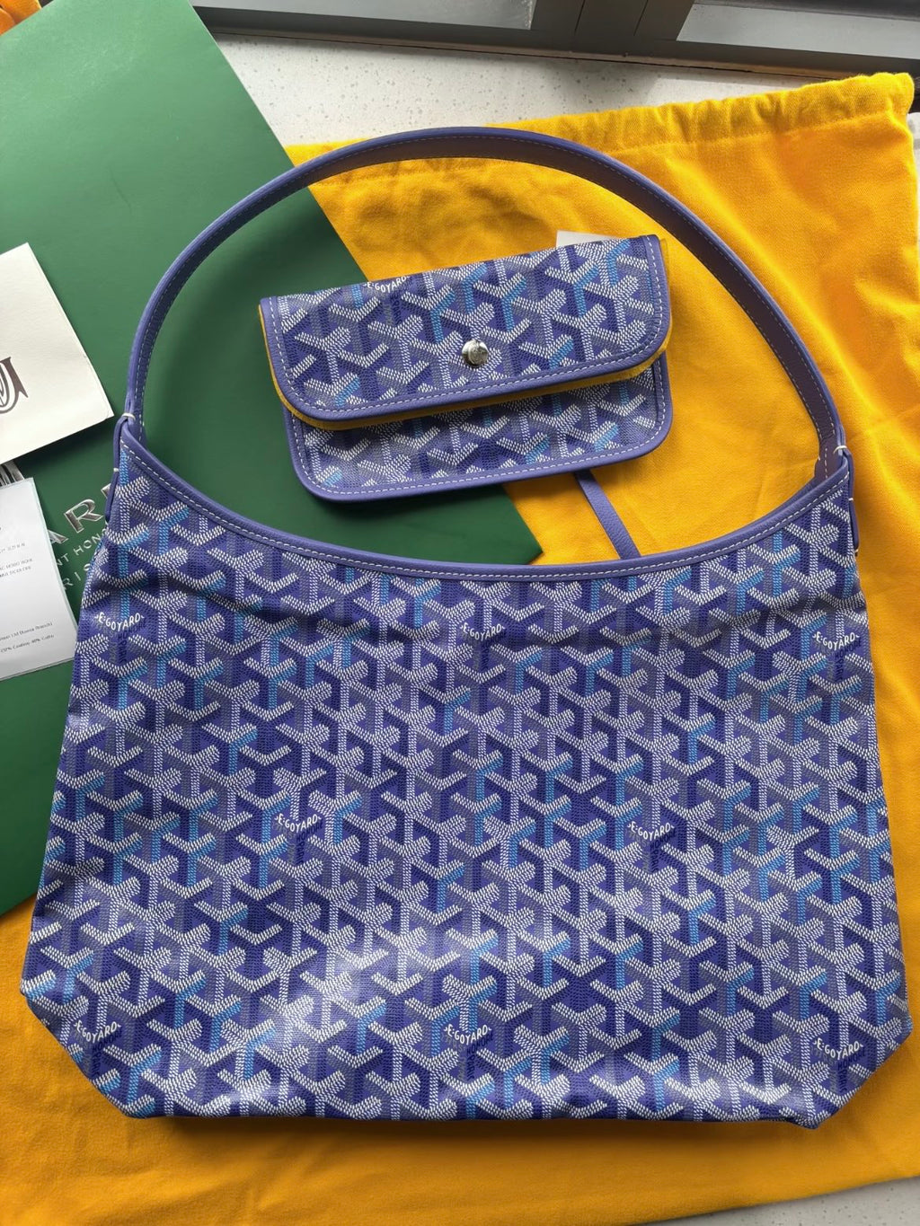 Blue patterned handbag with top handles and front flap pocket.