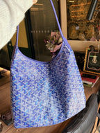Blue patterned shoulder bag with curved strap and open top.