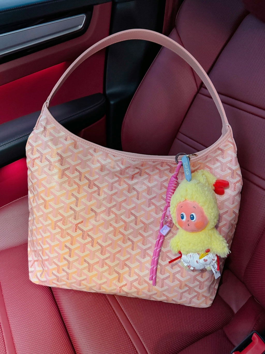 Light pink patterned handbag with wide top handles and hanging character charm