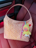 Light pink patterned handbag with wide top handles and hanging character charm