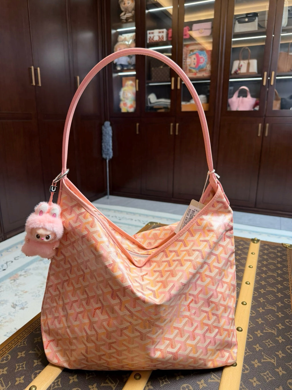 Pink patterned shoulder bag with long handles and small plush charm