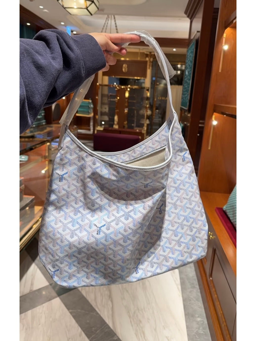 Goyard shoulder handbag in light blue with white pattern, open top, curved handles.