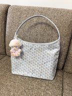Goyard handbag in light blue with white pattern and plush charm on strap.
