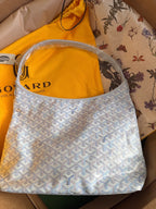 Goyard hobo handbag in light blue with white pattern, open top with dual handles.