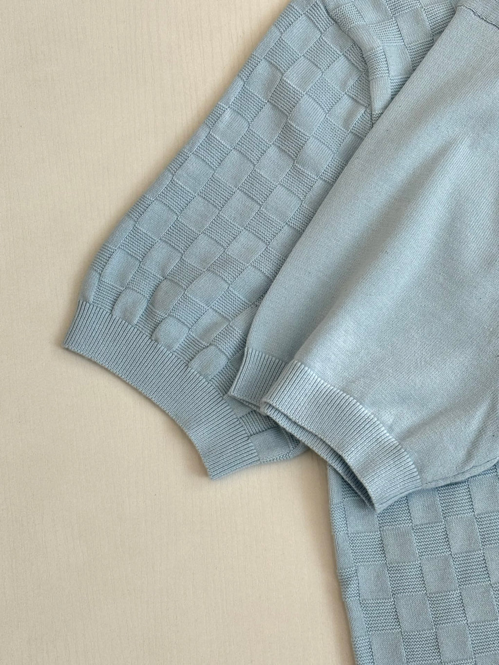 Light blue polo shirt sleeve and shoulder with textured checker-knit pattern