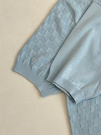 Light blue polo shirt sleeve and shoulder with textured checker-knit pattern