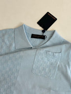 Light blue polo shirt close-up at collar and chest pocket with logo tag