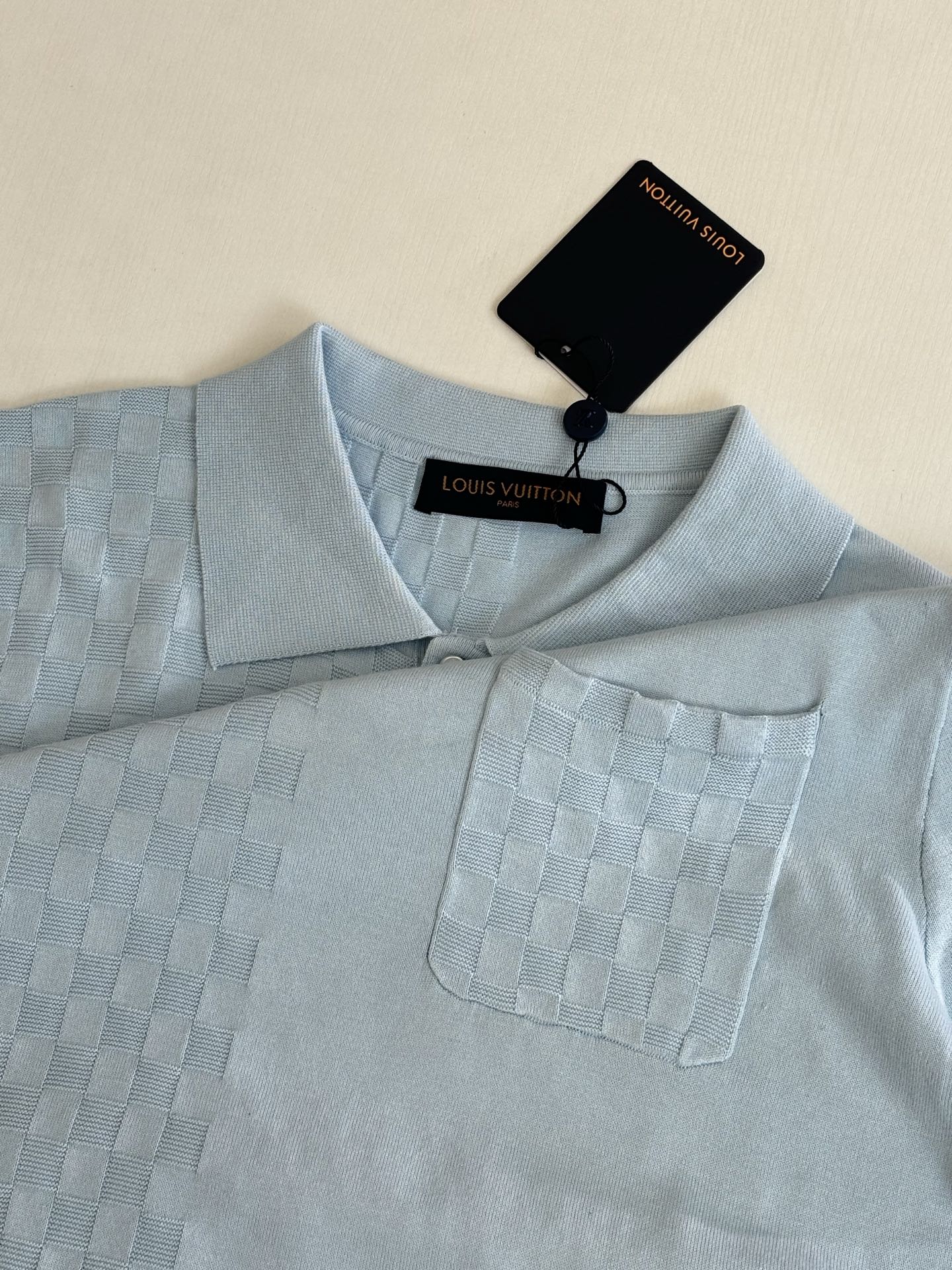 Light blue polo shirt close-up at collar and chest pocket with logo tag