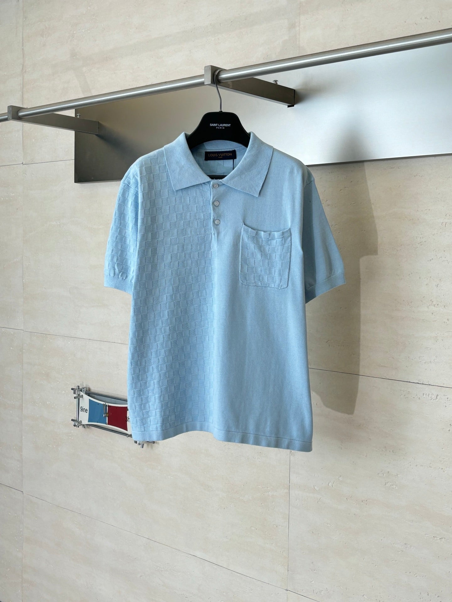 Light blue polo shirt with short sleeves, collar, button placket, and chest pocket