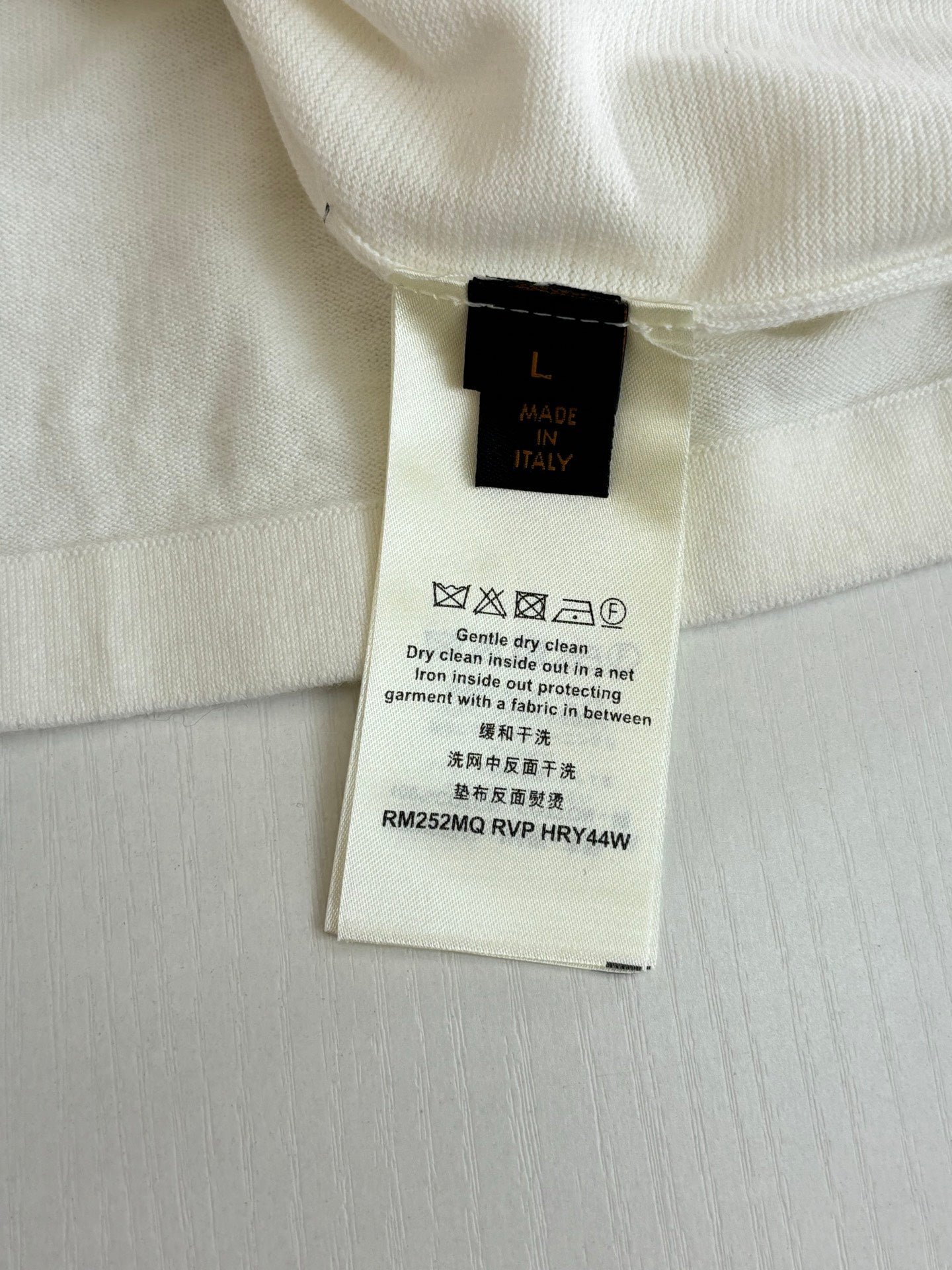 Louis Vuitton size and care label on a white polo shirt
