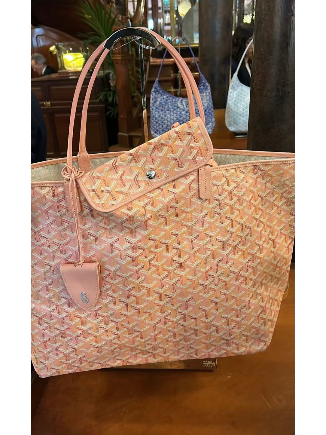 Pink patterned tote bag with top handles and front flap pouch detail, front view.