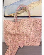 Pink patterned tote bag with top handles and detachable pouch, front view.