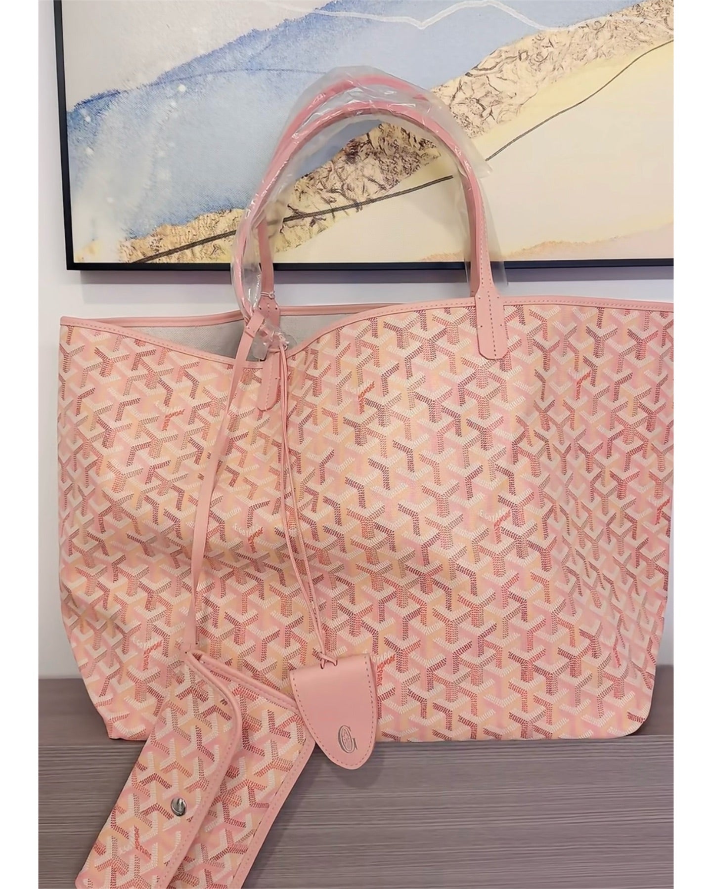 Pink patterned tote bag with top handles and detachable pouch, front view.
