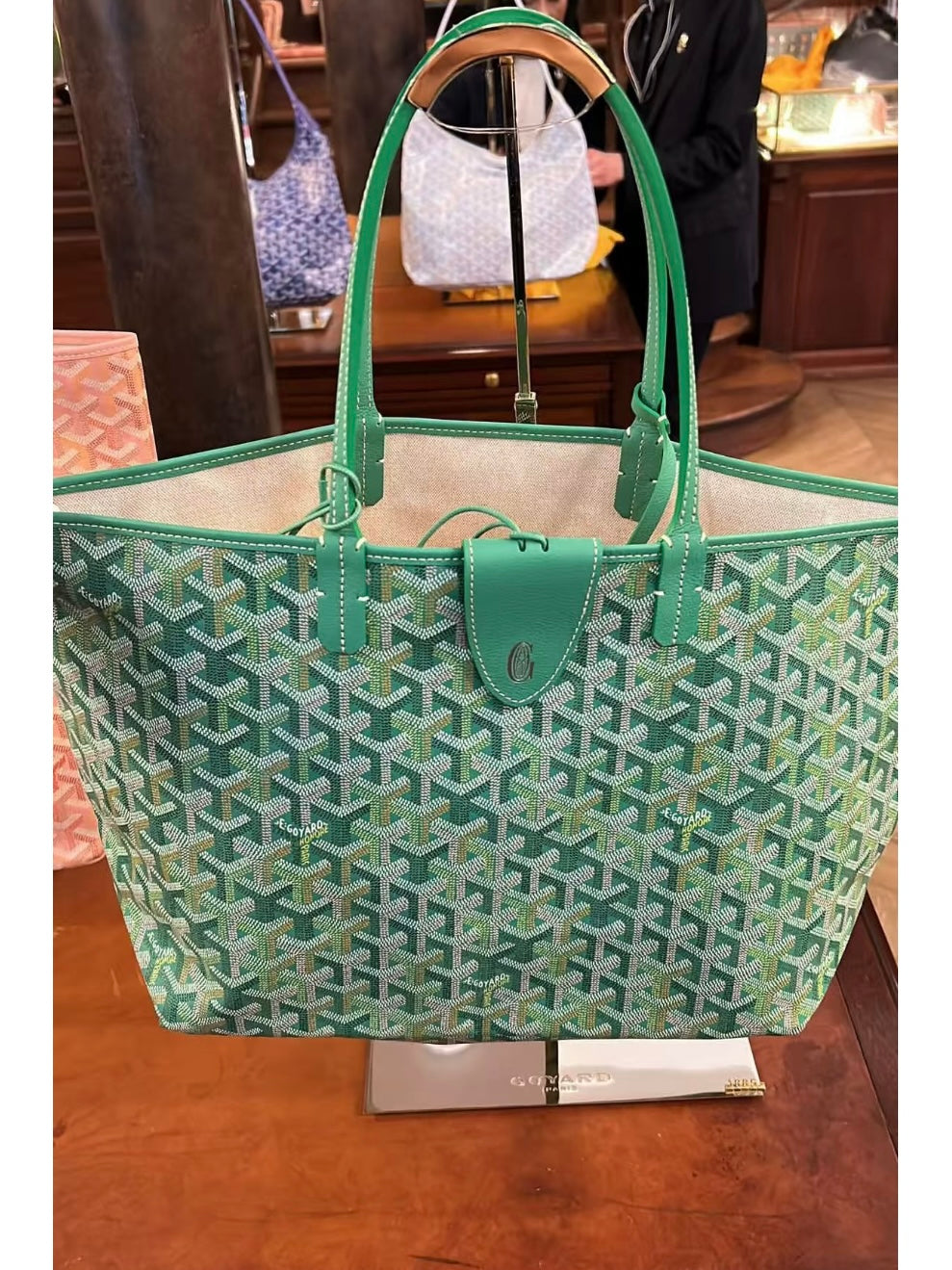 Green patterned tote bag with top handles and small front emblem