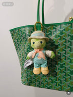 Green patterned tote bag with plush teddy keychain and hat charm