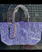 Blue patterned tote bag with top handles, front pocket, and hanging plush charm
