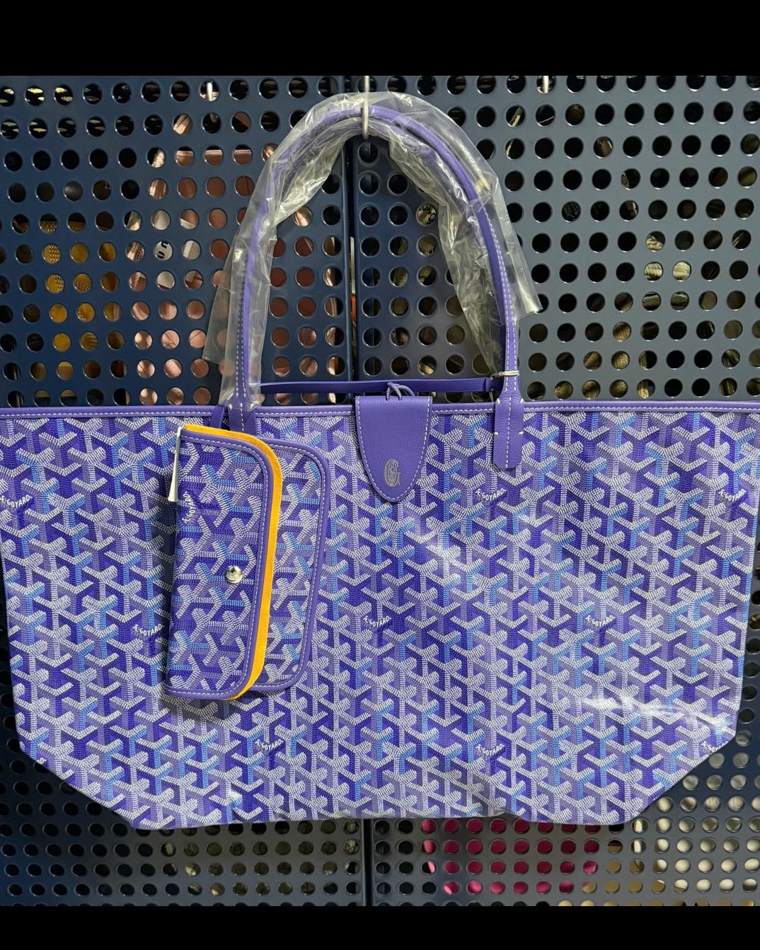 Blue patterned tote bag with top handles, front pocket, and hanging plush charm