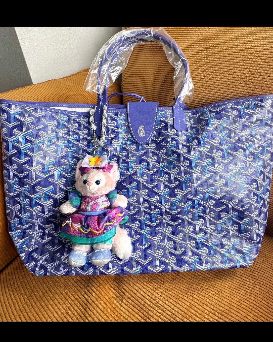 Blue patterned tote bag with top handles and a hanging doll plush keychain