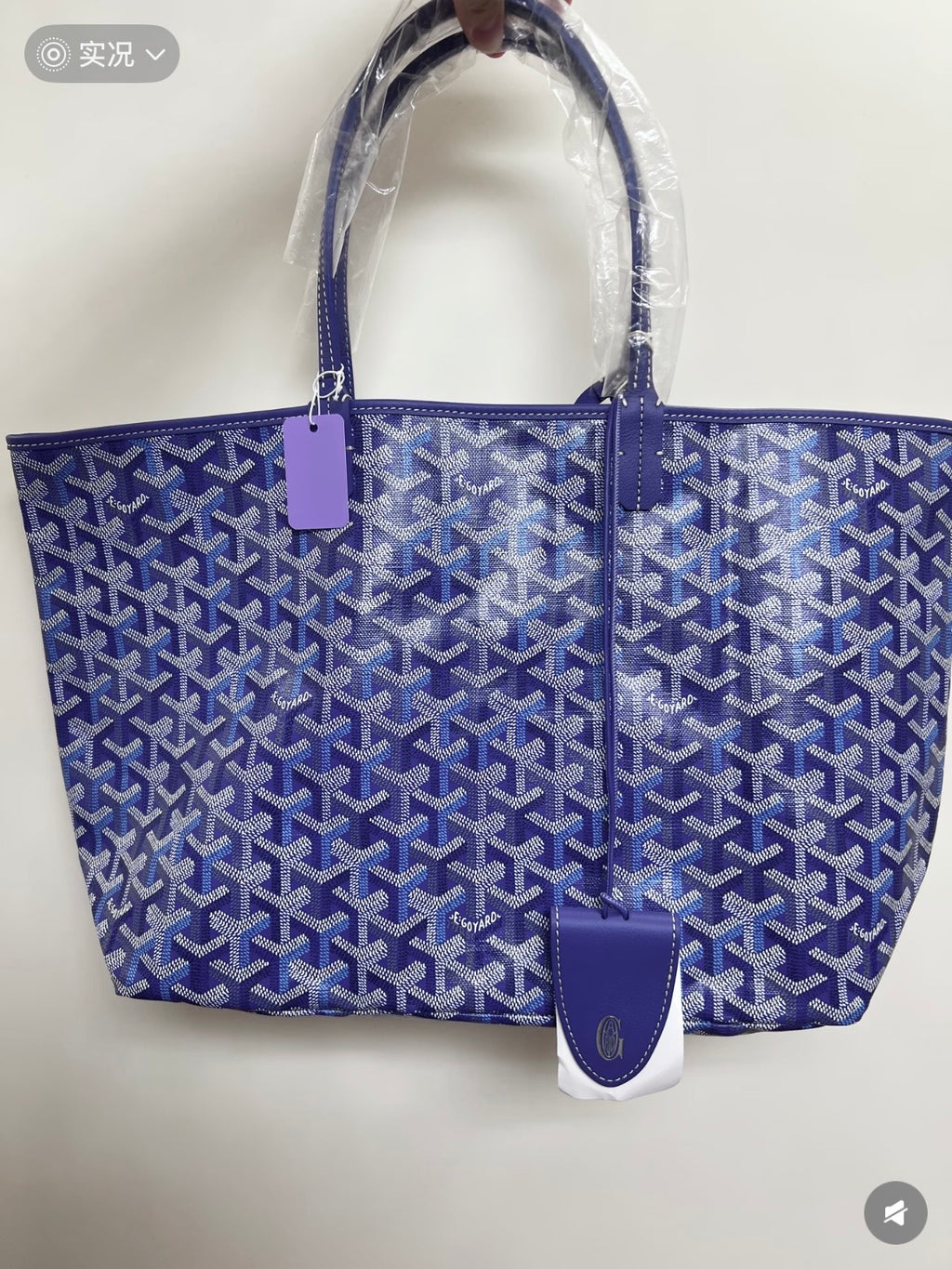 Blue patterned tote bag with top handles and leather logo patch, side view