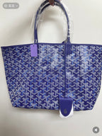 Blue patterned tote bag with top handles and leather logo patch, side view