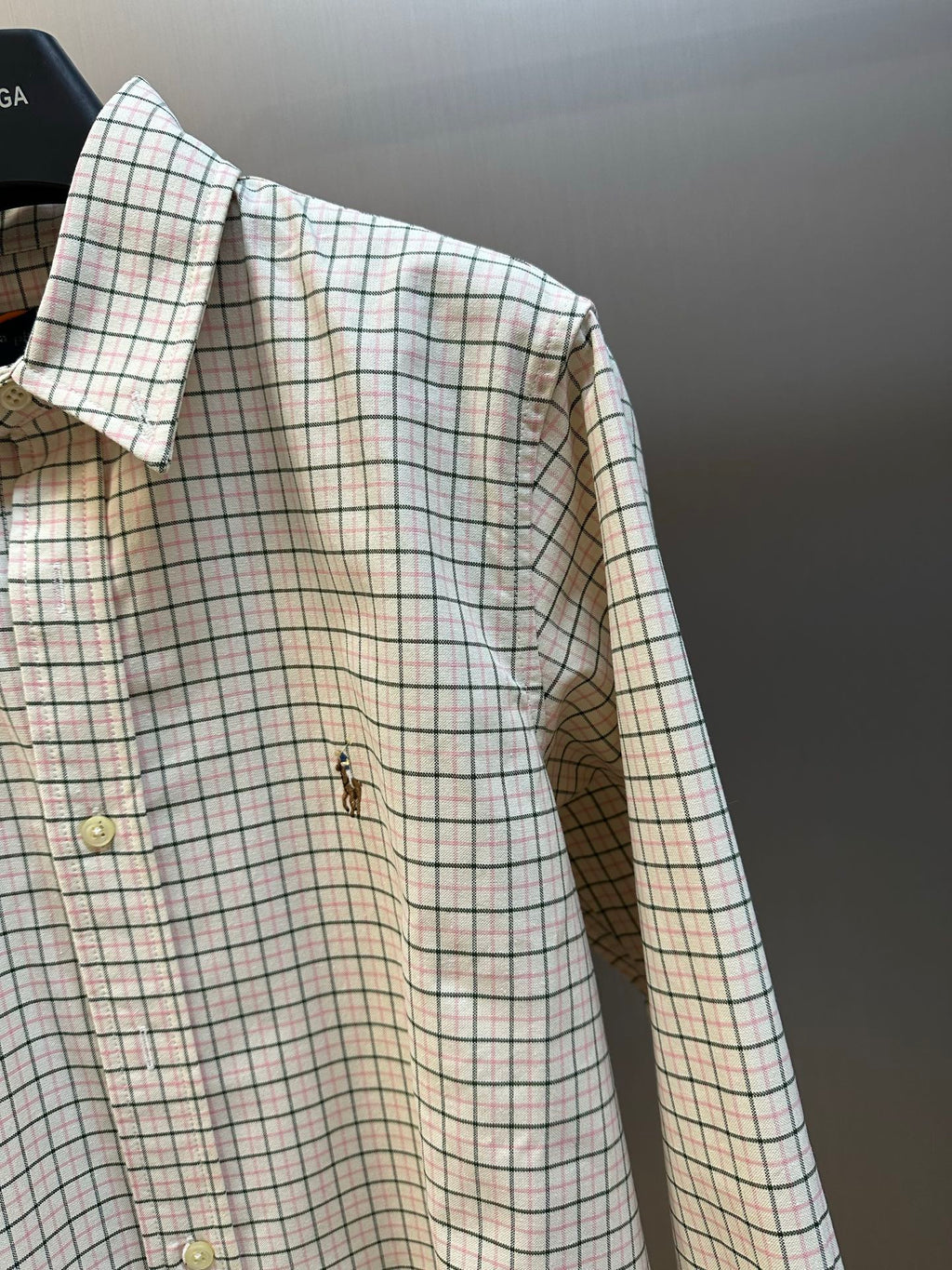 Plaid long-sleeve shirt side view with buttons and embroidered chest motif.