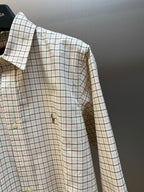 Plaid long-sleeve shirt side view with buttons and embroidered chest motif.