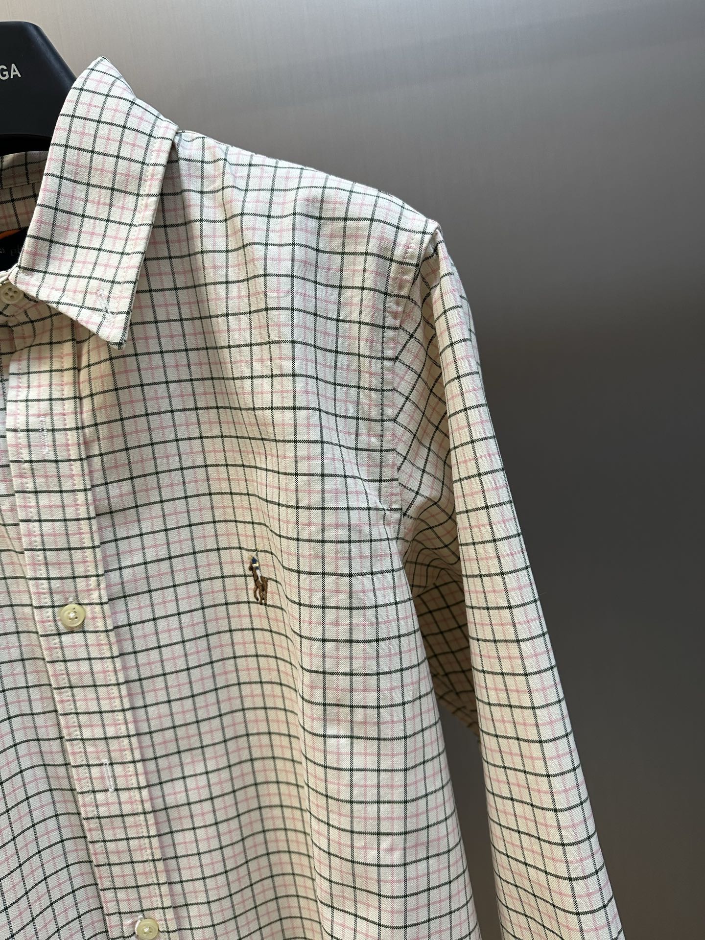 Plaid long-sleeve shirt side view with buttons and embroidered chest motif.