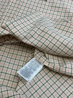 Folded plaid shirt with interior label and stitched seams.