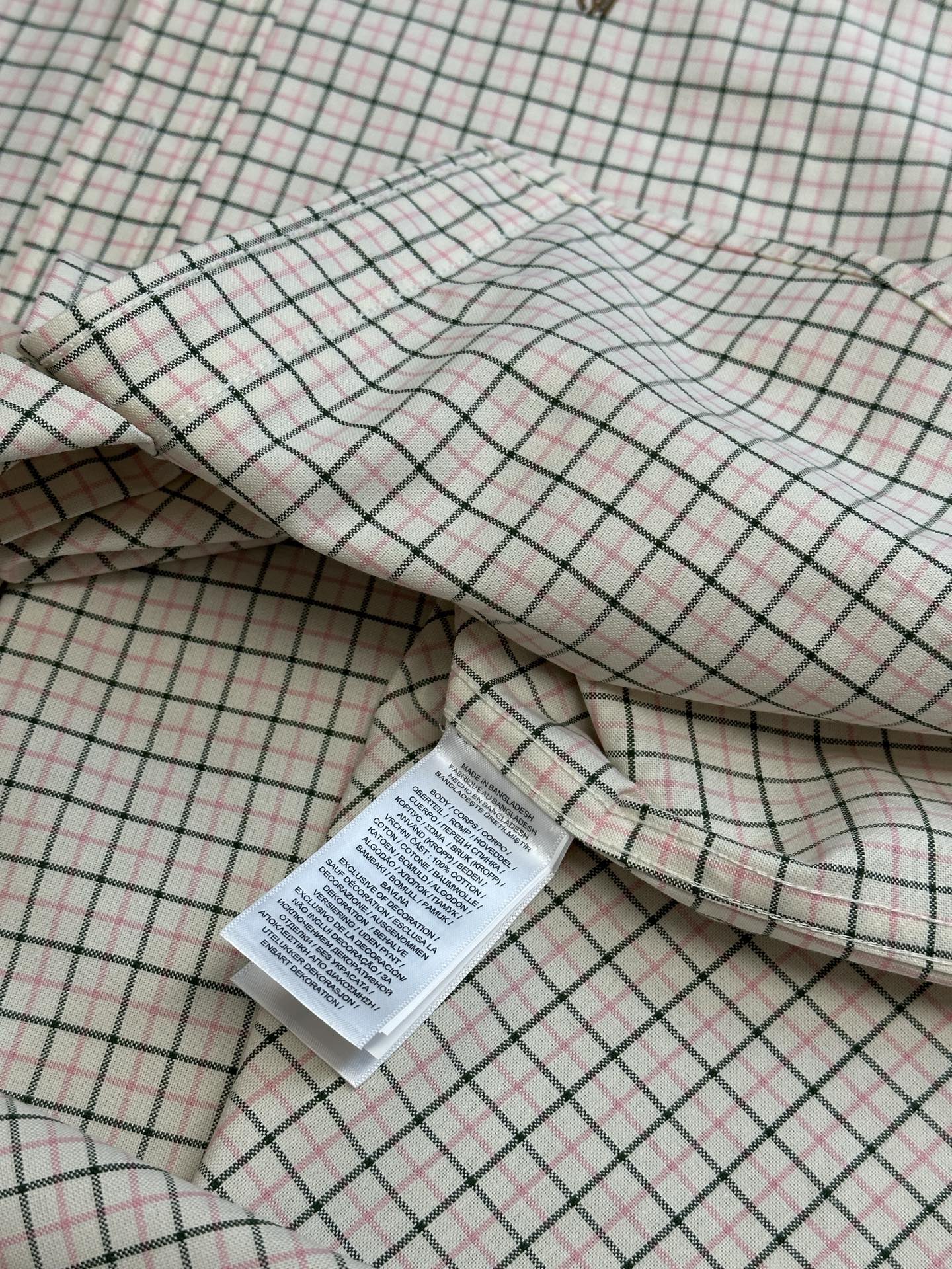 Folded plaid shirt with interior label and stitched seams.