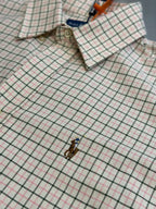 Plaid shirt close-up showing embroidered logo and buttoned cuffs.