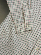 Plaid shirt cuff and hem close-up with button detail and stitching.