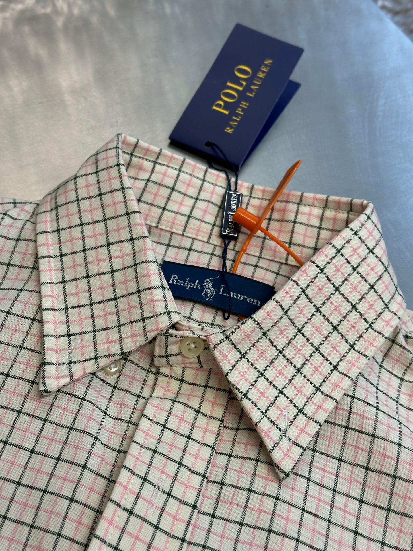 Plaid button-up shirt front with tags, spread collar, and button placket.