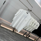 White short-sleeve T-shirt with small chest pocket and logo detail, on hangers