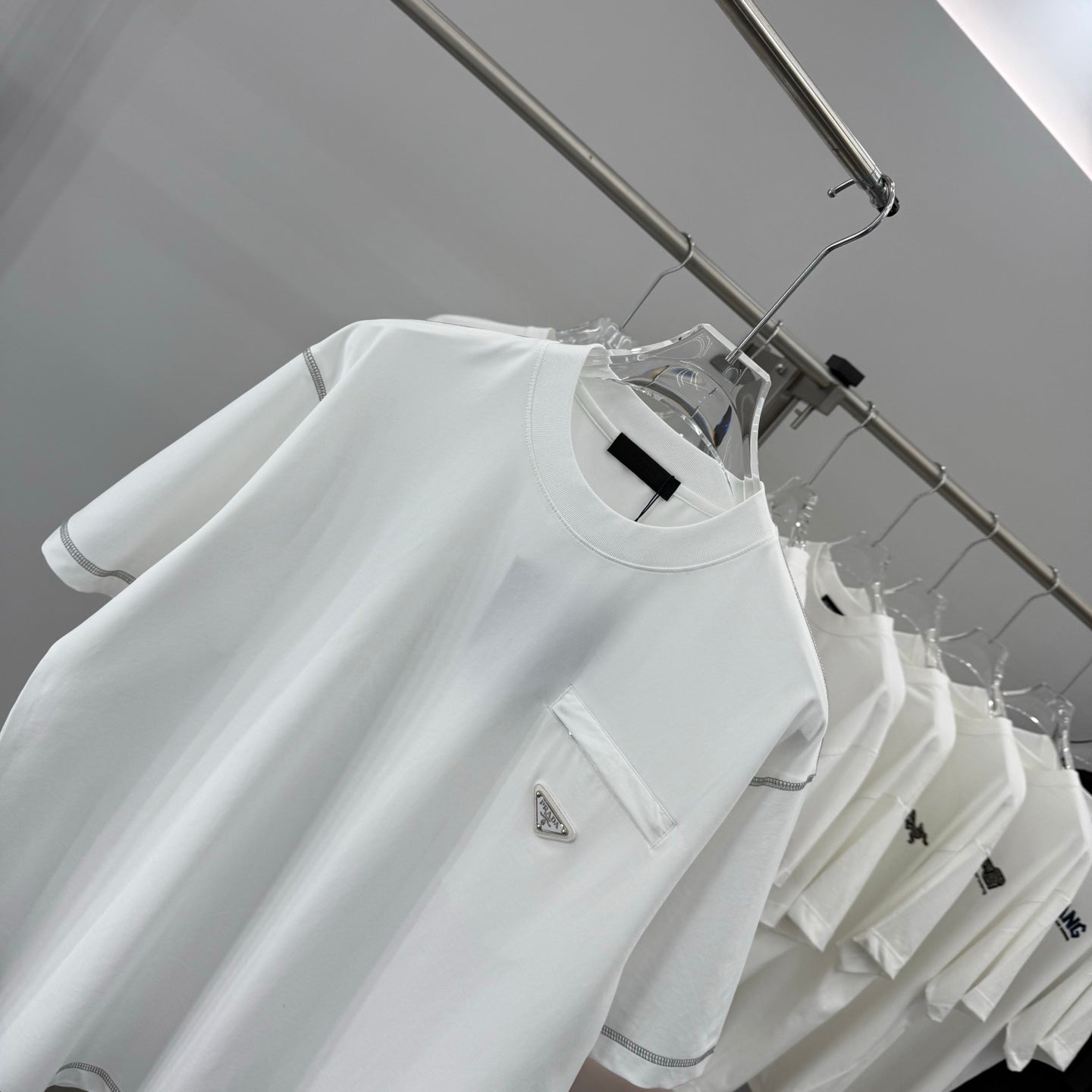 White short-sleeve crewneck T-shirt with chest pocket and triangular logo patch