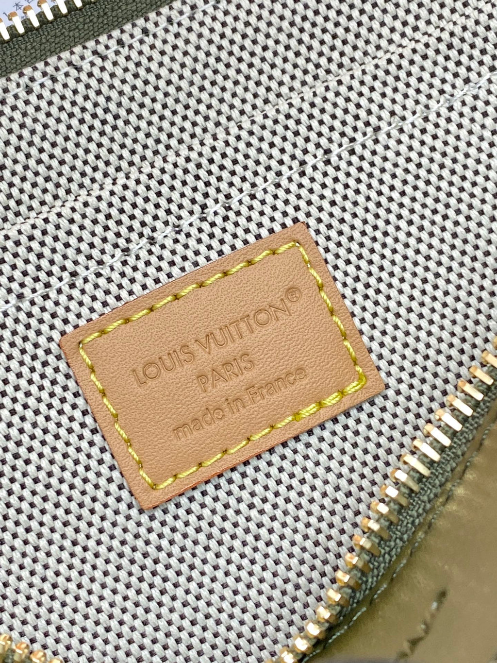 Louis Vuitton monogram bag close-up of leather logo patch and gold zipper