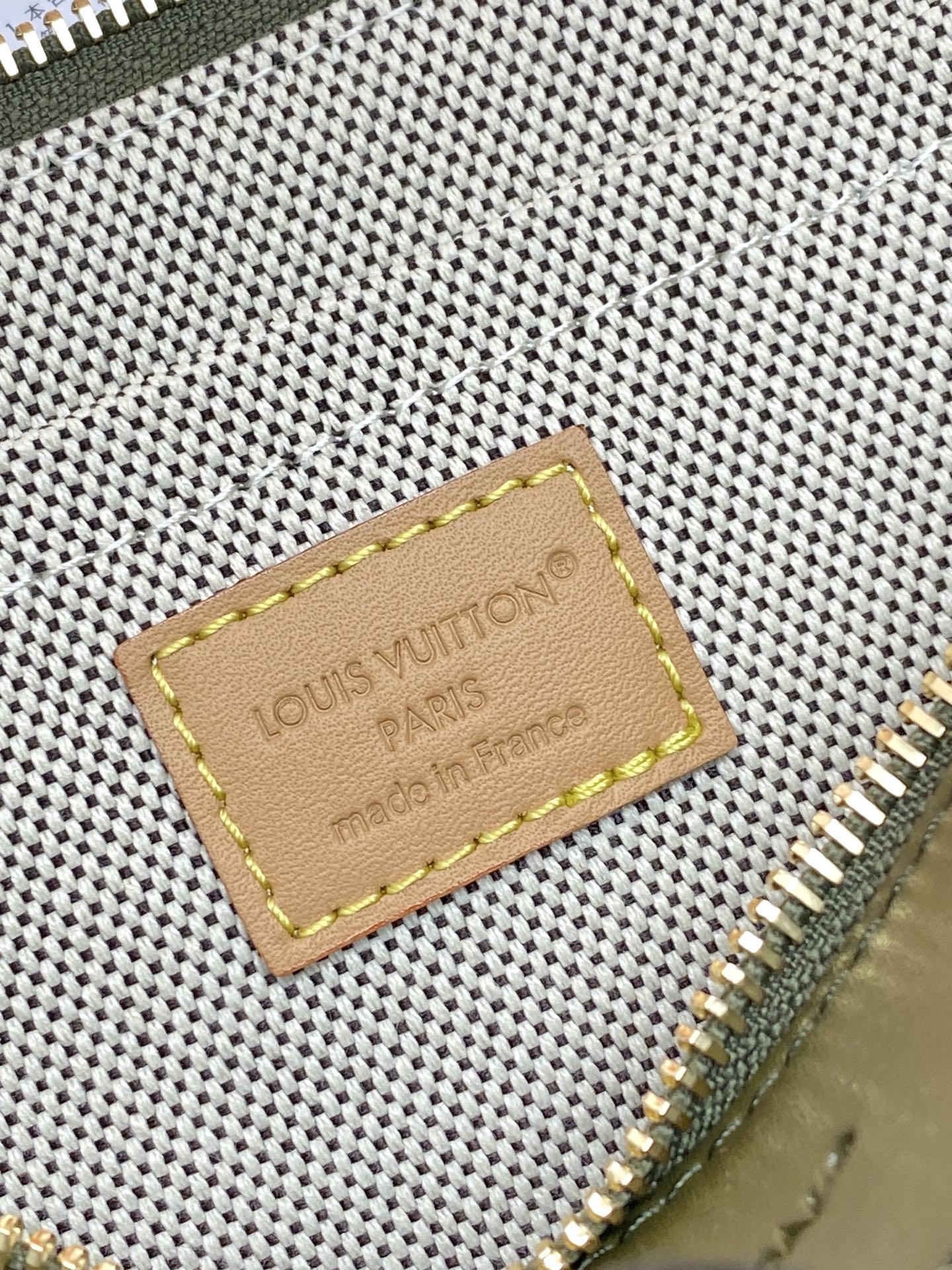 Louis Vuitton monogram bag close-up of leather logo patch and gold zipper