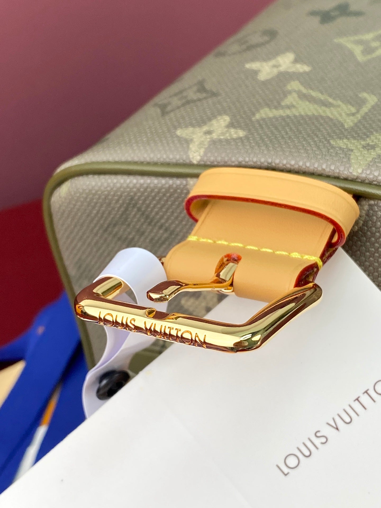 Open monogram bag showing brass latch and interior lining, olive exterior
