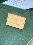 Green leather logo patch with yellow stitching on an olive bag panel