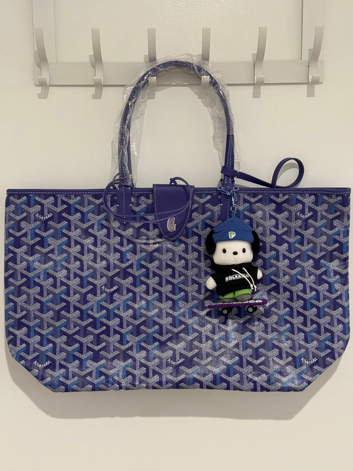 Blue patterned tote bag with two top handles and a hanging plush doll keychain