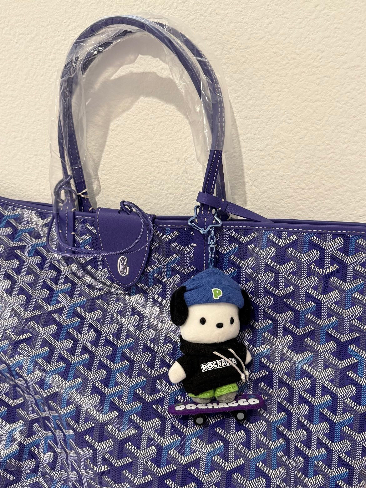 Blue patterned tote bag with leather handles and a hanging plush charm