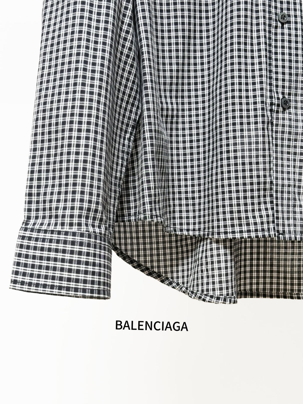Checkered button-up shirt sleeve with buttoned cuff and rounded curved hem