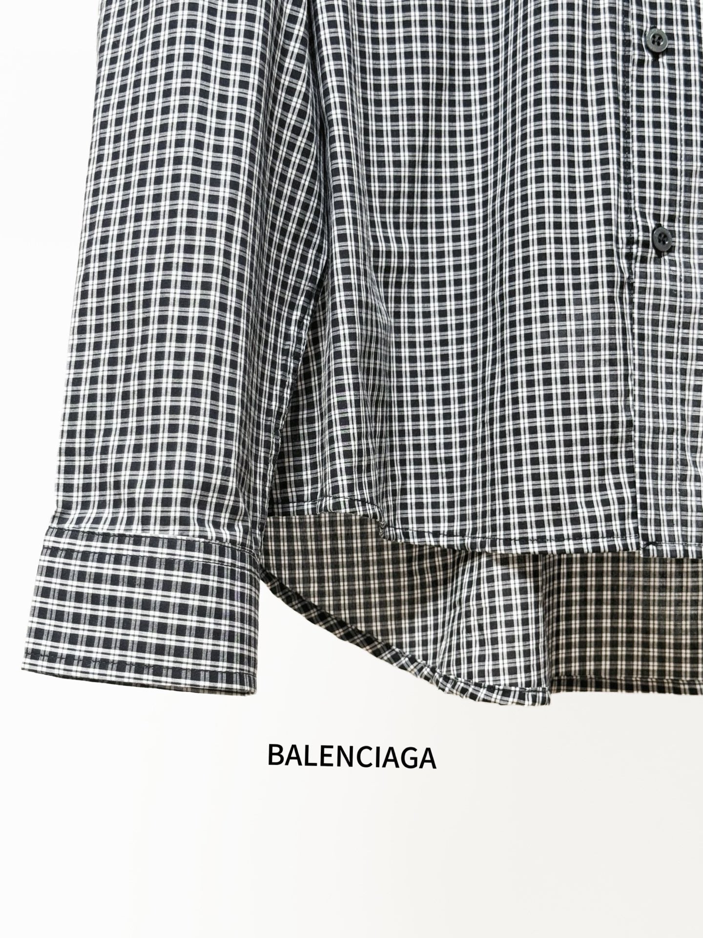 Checkered button-up shirt sleeve with buttoned cuff and rounded curved hem