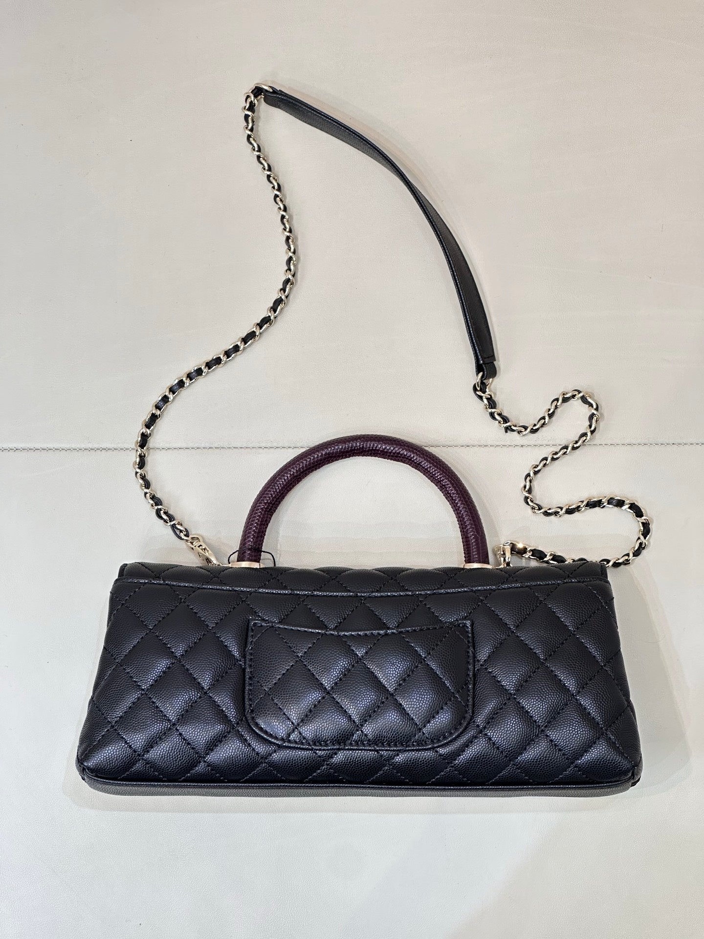 Chanel bag front view in dark navy quilted leather with purple handle and long chain