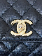Chanel bag close-up: gold CC emblem on dark navy quilted leather