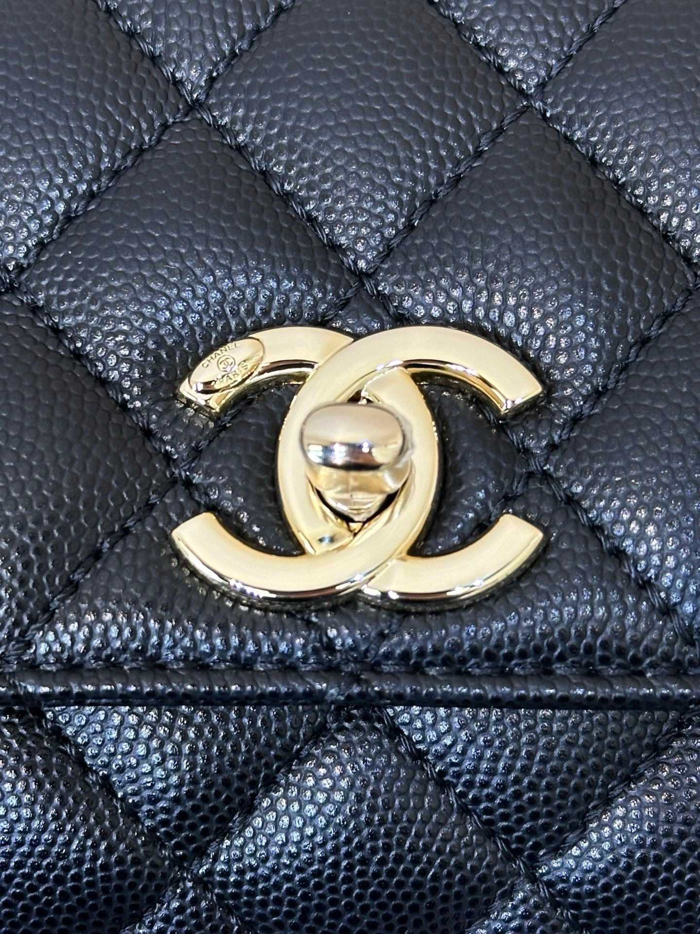 Chanel bag close-up: gold CC emblem on dark navy quilted leather