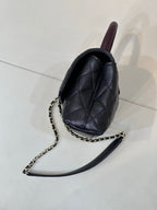 Chanel bag side view in dark navy quilted leather with purple top handle and chain
