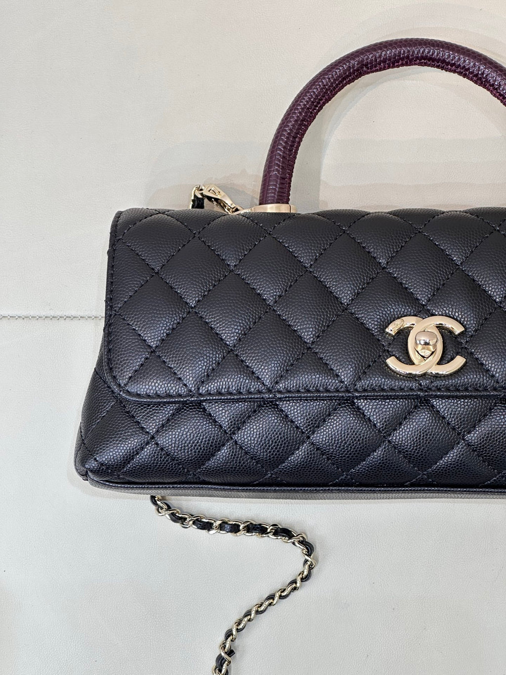 Chanel bag close-up: dark navy quilted flap, purple top handle, gold CC emblem