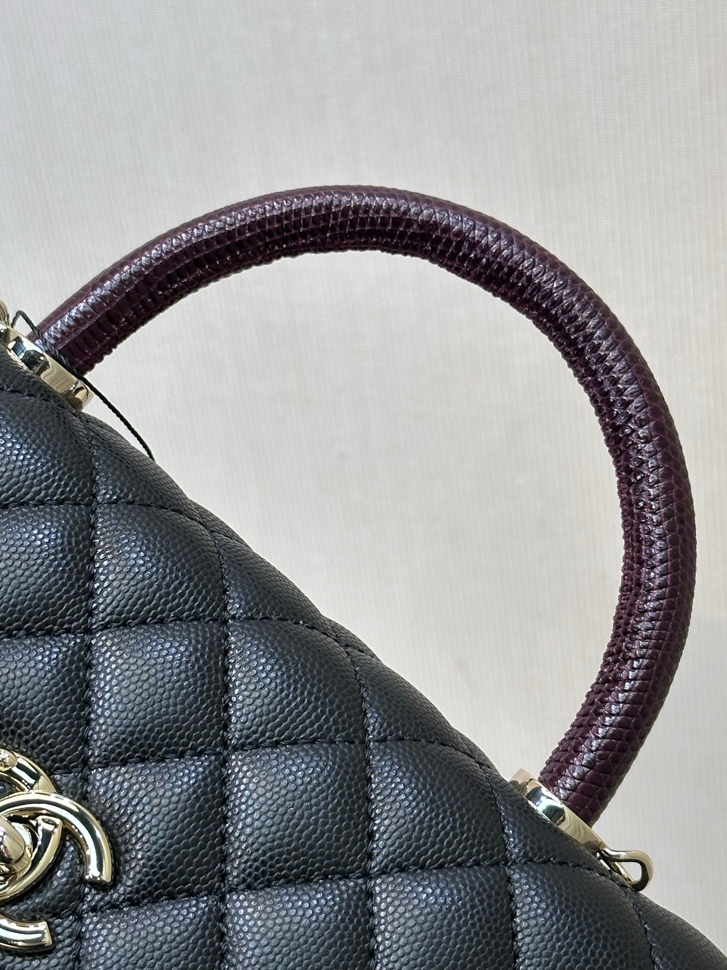 Chanel bag close-up: textured dark navy leather with purple top handle and metal clasp