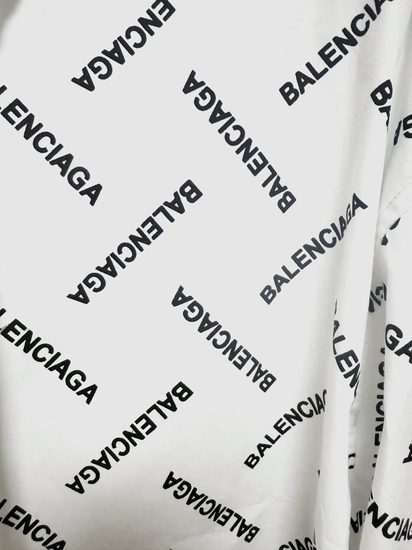 White long-sleeve button-up shirt fabric detail with black Balenciaga logo print
